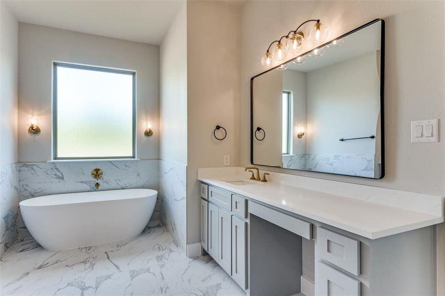 Full bathroom featuring vanity, a freestanding bath, light marble finish flooring, tile walls, and a wainscoted wall Full bathroom featuring vanity, a freestanding bath, light marble finish flooring, tile walls, and a wainscoted wall
