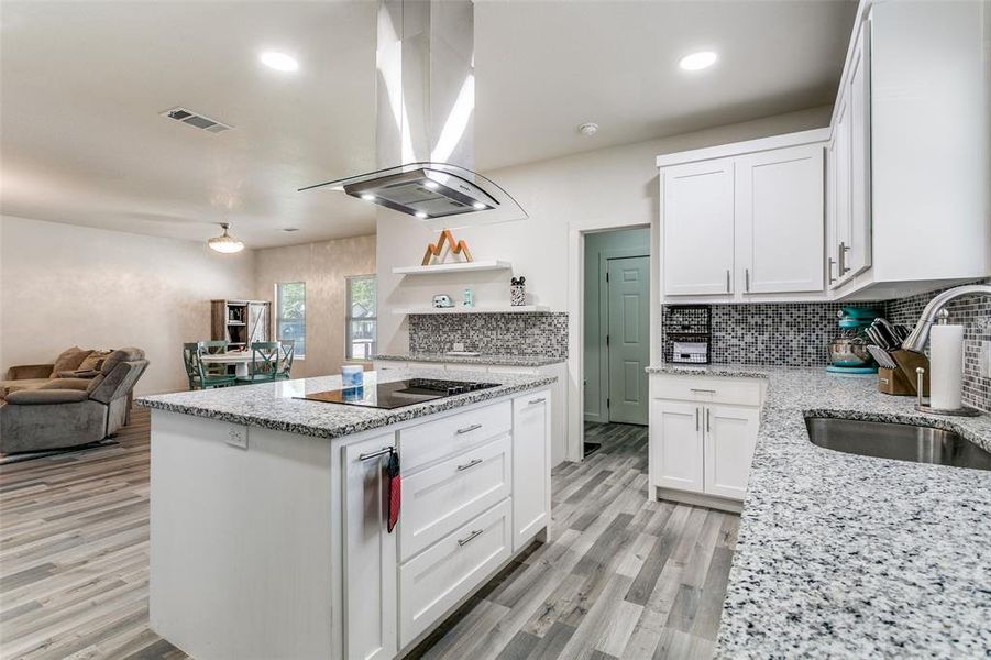 Kitchen with a kitchen island, stainless steel appliances, white cabinets, decorative backsplash, and light stone countertops Kitchen with a kitchen island, stainless steel appliances, white cabinets, decorative backsplash, and light stone countertops