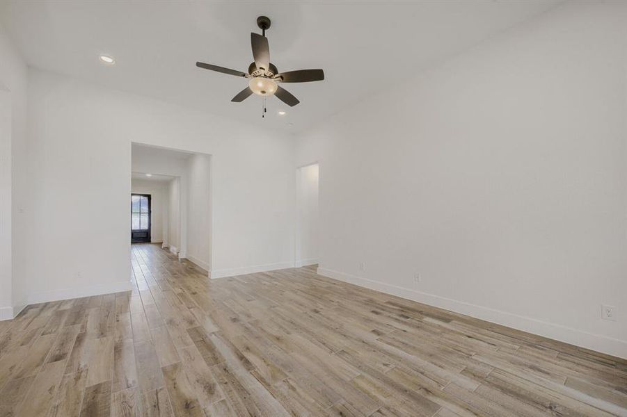 Spacious room featuring light wood-finish flooring, recessed lighting, and a ceiling fan with integrated light fixture