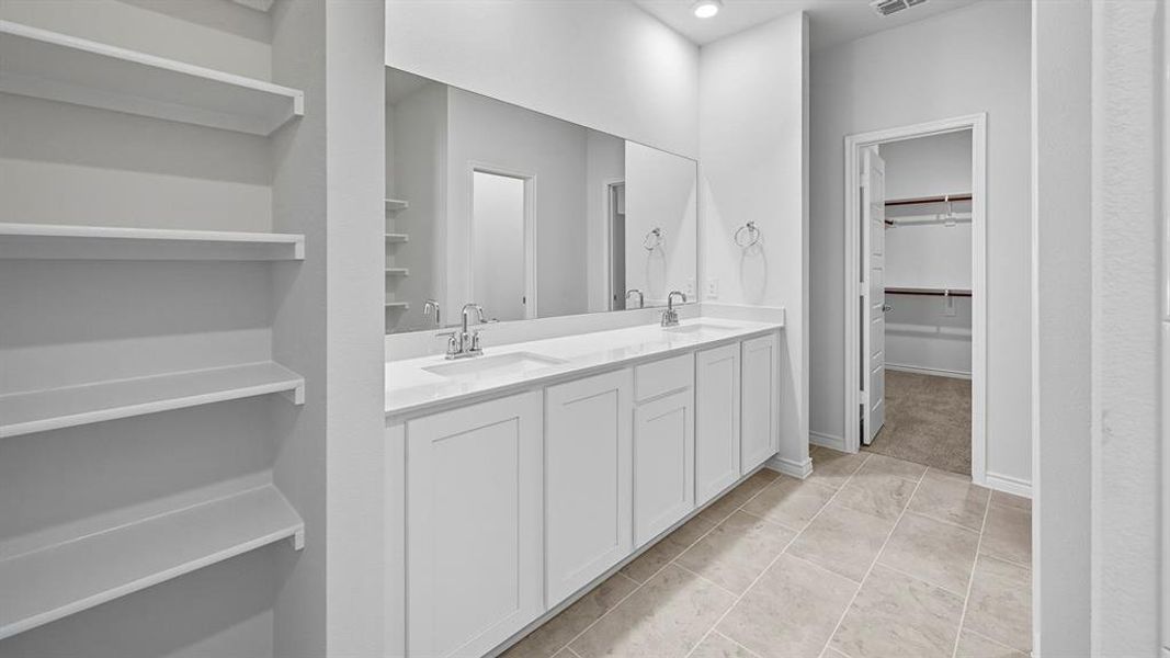Bathroom featuring a walk in closet and double vanity Bathroom featuring a walk in closet and double vanity