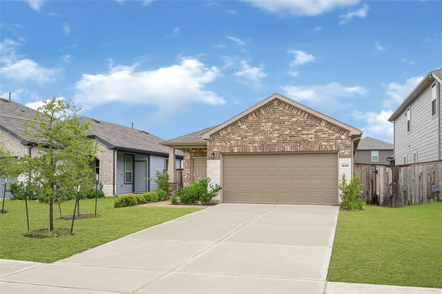 Front exterior view showcasing Alternative front view highlighting the neat concrete driveway and cozy covered front entryway.the home's striking curb appeal and beautifully landscaped front yard.