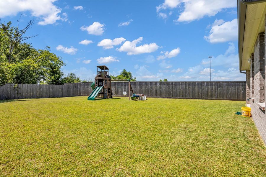 Spacious backyard is enclosed by a tall wooden fence, providing a private outdoor setting for gatherings, play, gardening, or simply enjoying time outside. With plenty of room to spread out, it offers flexibility for a variety of outdoor activities.