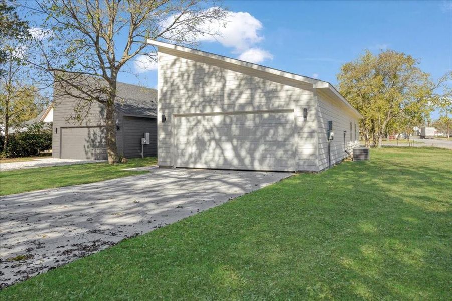 View of side of property with a yard and central AC