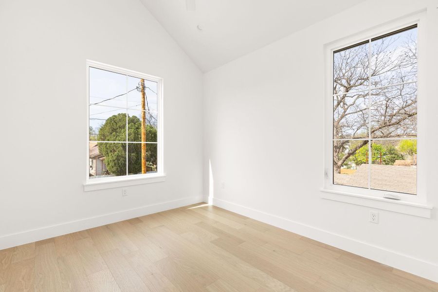 Spare room with light wood-style floors, lofted ceiling, and healthy amount of natural light Spare room with light wood-style floors, lofted ceiling, and healthy amount of natural light