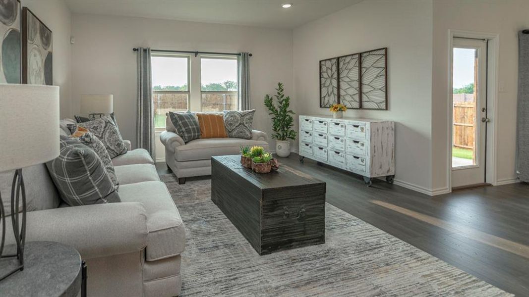 Bright living area featuring wood-finish flooring, light neutral wall tones, recessed lighting, a built-in wall cabinet, and a glass-paneled exterior door