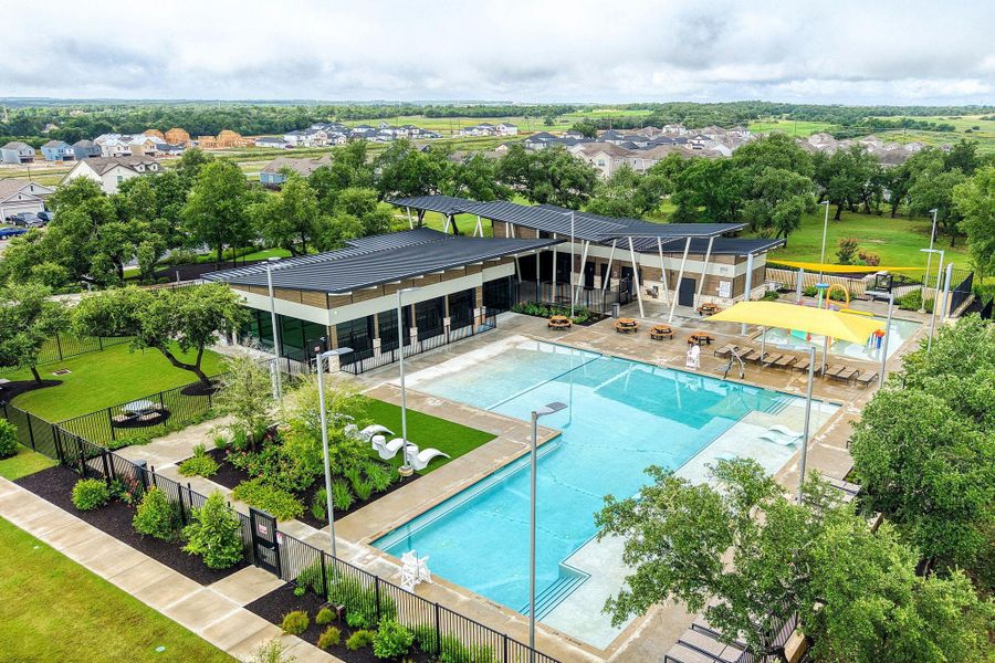 An aerial view captures the vibrant community amenities, featuring a sparkling pool, modern clubhouse, and abundant green space. An aerial view captures the vibrant community amenities, featuring a sparkling pool, modern clubhouse, and abundant green space.