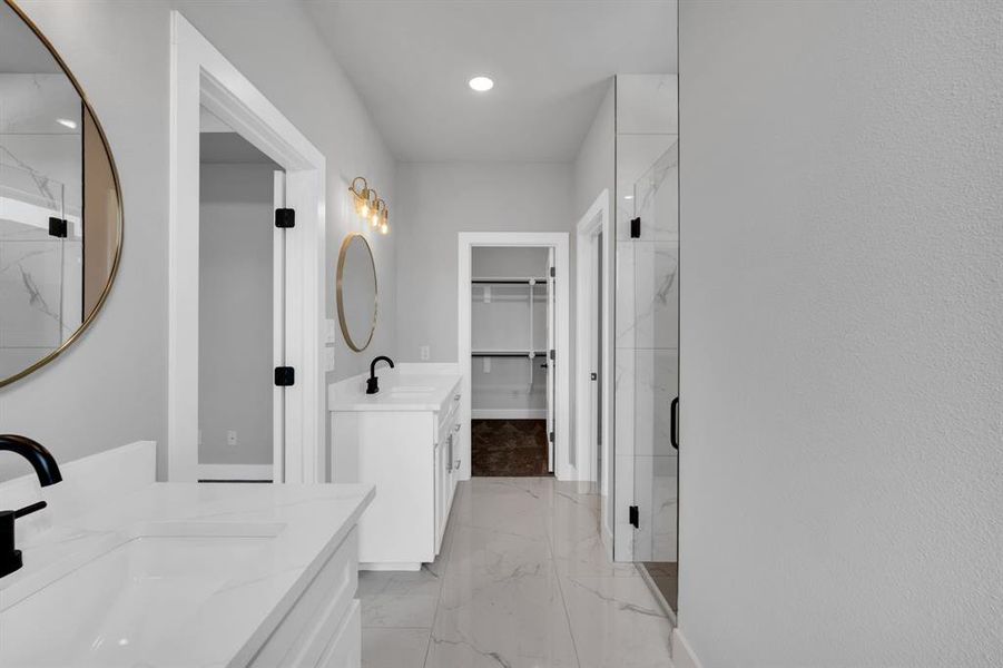 Bathroom with double sink vanity, a shower with door, and tile patterned flooring