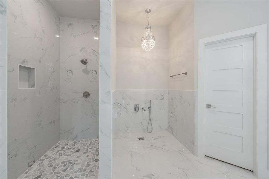 Bathroom featuring tile walls, a marble finish shower, a chandelier, and marble finish floors