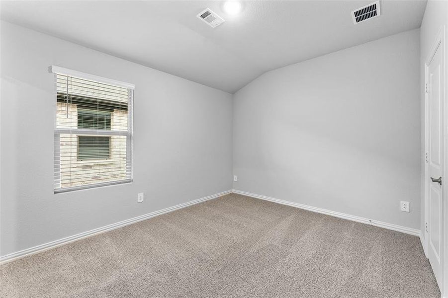 Carpeted spare room with vaulted ceiling and baseboards Carpeted spare room with vaulted ceiling and baseboards