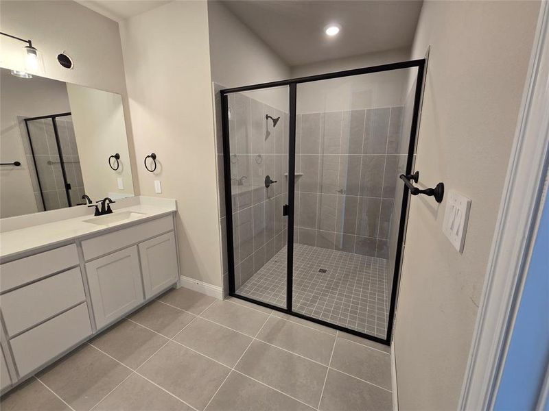 Full bathroom featuring vanity, light tile patterned floors, and a stall shower