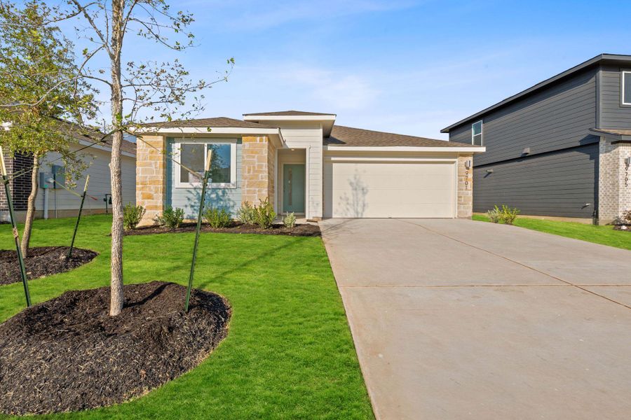 View of front of home with stone siding, a front lawn, driveway, and roof with shingles
