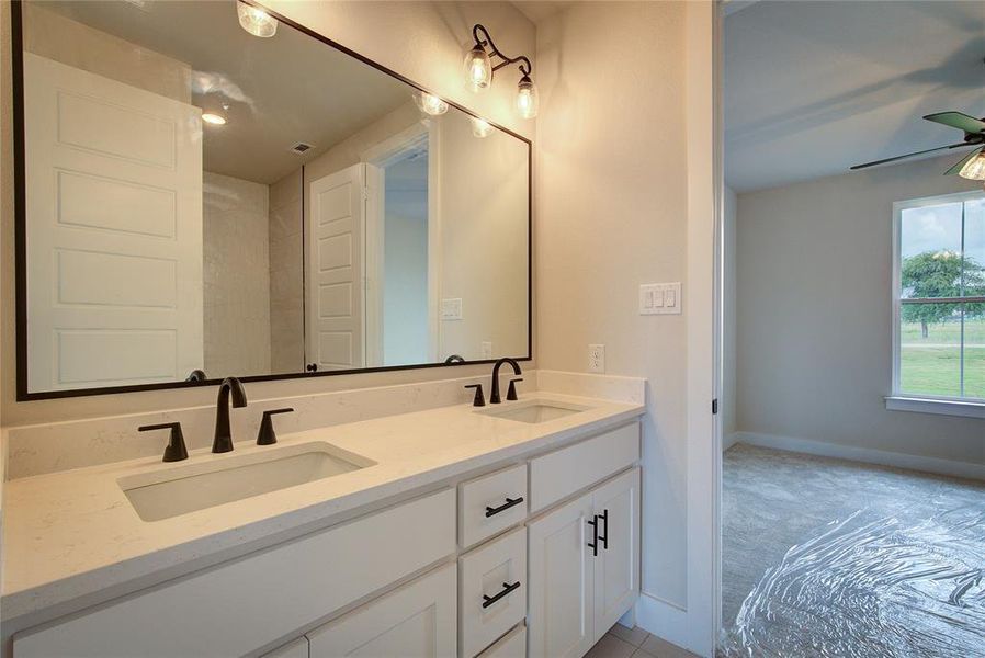 Bathroom featuring dual sinks, ceiling fan, and large vanity