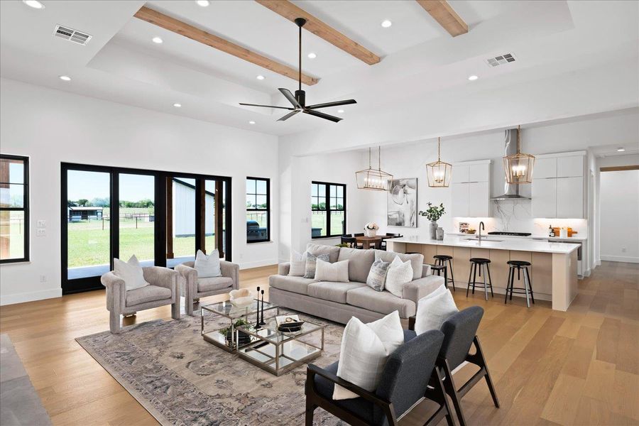 Living room with light wood-style floors, recessed lighting, beam ceiling, a high ceiling, and baseboards