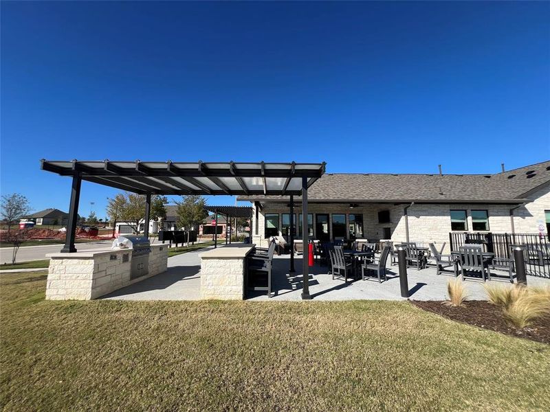 Surrounding community featuring a yard, a patio, a pergola, and exterior kitchen just off of the pool and the club house.