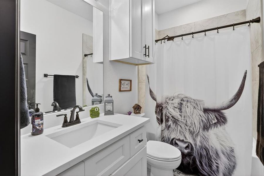Bathroom featuring a white vanity with an integrated sink, dark bronze-finish fixtures, and a frameless mirror
