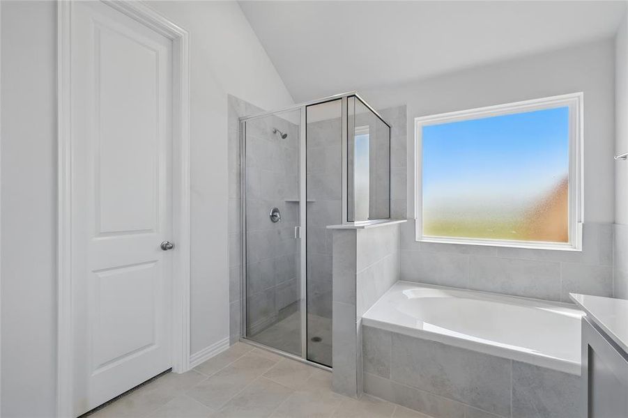 Bathroom featuring a stall shower, a garden tub, lofted ceiling, and tile patterned floors Bathroom featuring a stall shower, a garden tub, lofted ceiling, and tile patterned floors