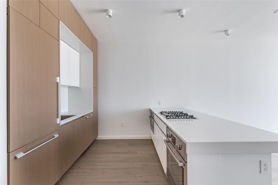 A well-lit, contemporary kitchen showcasing sleek cabinetry and a sophisticated cooking range. A well-lit, contemporary kitchen showcasing sleek cabinetry and a sophisticated cooking range.