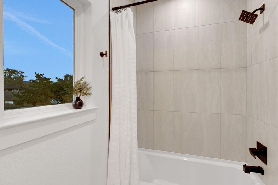 Full bath featuring a deep soaking tub with modern tile surround and a large window that brings in natural light, creating a relaxing retreat. Full bath featuring a deep soaking tub with modern tile surround and a large window that brings in natural light, creating a relaxing retreat.