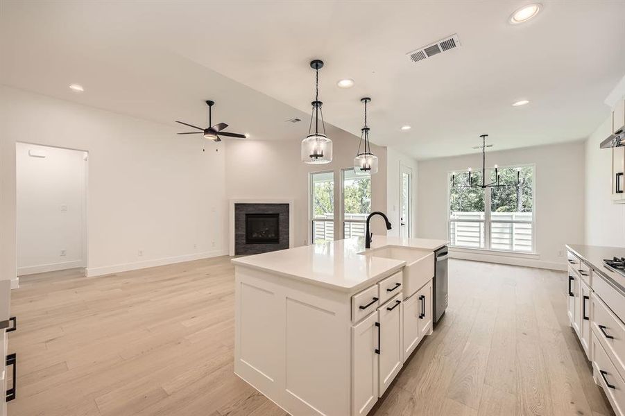 Kitchen with a fireplace, a sink, a ceiling fan, light wood finished floors, and pendant lighting
