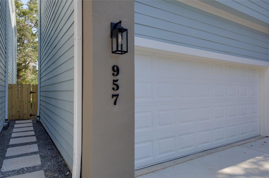 Modern address column in stucco with sleek sconce beside the oversized two-car garage. Clean Hardie-siding, fresh paint, and a low-maintenance paver walkway along the side yard leading to the gated backyard. Modern address column in stucco with sleek sconce beside the oversized two-car garage. Clean Hardie-siding, fresh paint, and a low-maintenance paver walkway along the side yard leading to the gated backyard.