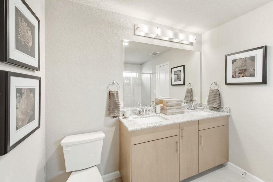 Bathroom with double sink vanity, granite countertop, light wood cabinets, and large mirror with overhead lighting Bathroom with double sink vanity, granite countertop, light wood cabinets, and large mirror with overhead lighting