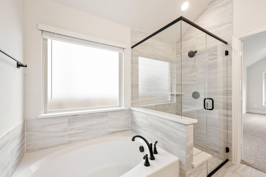 Master bathroom with soaking tub, glass-enclosed shower, gray tile walls, and black fixtures Master bathroom with soaking tub, glass-enclosed shower, gray tile walls, and black fixtures
