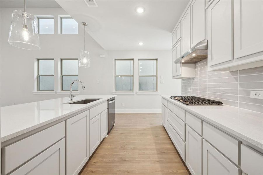 Kitchen with appliances with stainless steel finishes, decorative light fixtures, sink, and white cabinets