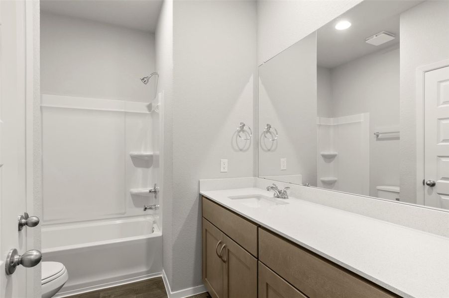 Full bath featuring vanity, washtub / shower combination, and wood finished floors