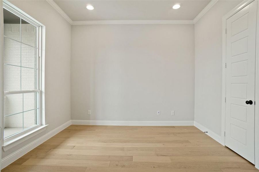 Spare room featuring crown molding and light wood-type flooring