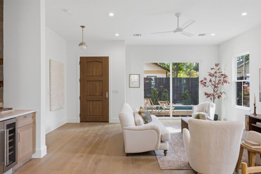 Bright, open living space with hardwood flooring extends to an inviting outdoor pool area.