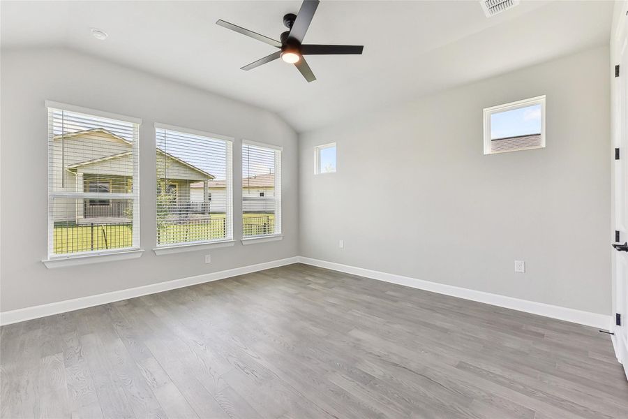 Empty room featuring vaulted ceiling, ceiling fan, wood finished floors, and baseboards Empty room featuring vaulted ceiling, ceiling fan, wood finished floors, and baseboards