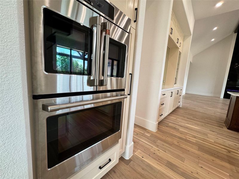 Spacious prep kitchen and pantry serves as the perfect extension of the gourmet chef's kitchen. Thoughtfully positioned behind the main kitchen, this dedicated workspace features extensive quartz countertops, custom cabinetry, open display shelving, a secondary sink, abundant storage, and ample prep space for entertaining. Ideal for meal preparation, serving, coffee station setup, or keeping small appliances tucked away