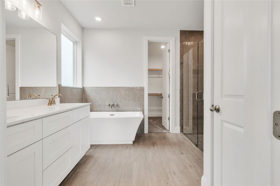A well-lit primary bathroom features a standalone tub, glass-enclosed shower, and a double vanity.