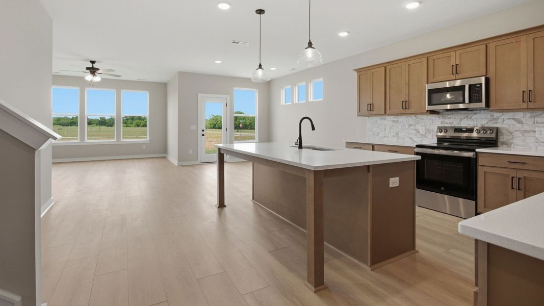 Kitchen with quartz countertops, tile backsplash, and view of gathering room Kitchen with quartz countertops, tile backsplash, and view of gathering room