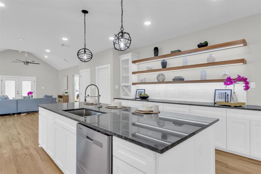 Kitchen with white cabinetry, open floor plan, dishwasher, open shelves, and vaulted ceiling