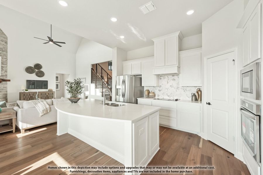 Open kitchen with white cabinets, curved island, marble backsplash, and stainless steel appliances, open to living area with hardwood floors. Open kitchen with white cabinets, curved island, marble backsplash, and stainless steel appliances, open to living area with hardwood floors.