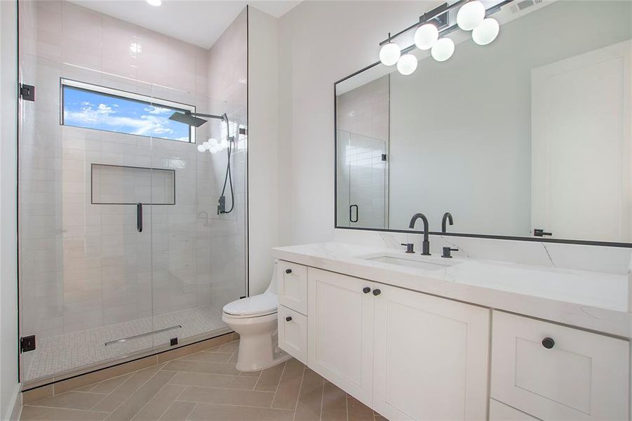 Bathroom featuring tile patterned floors, vanity, an enclosed shower, and toilet