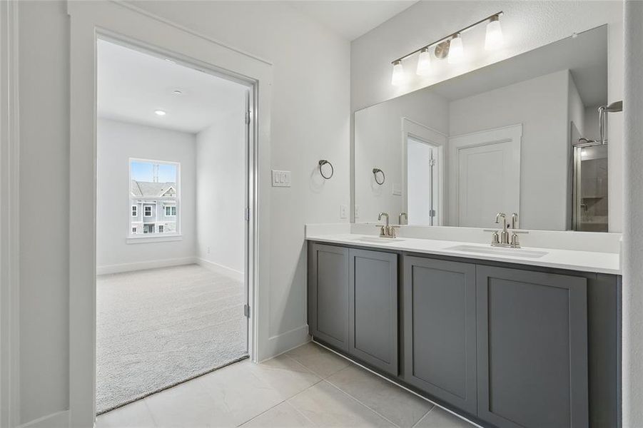 Full bath featuring double vanity, light carpet, and light tile patterned floors