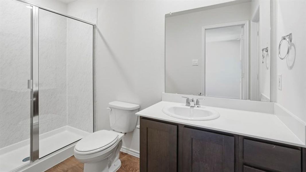 Full bath with vanity, a stall shower, and dark wood-style floors