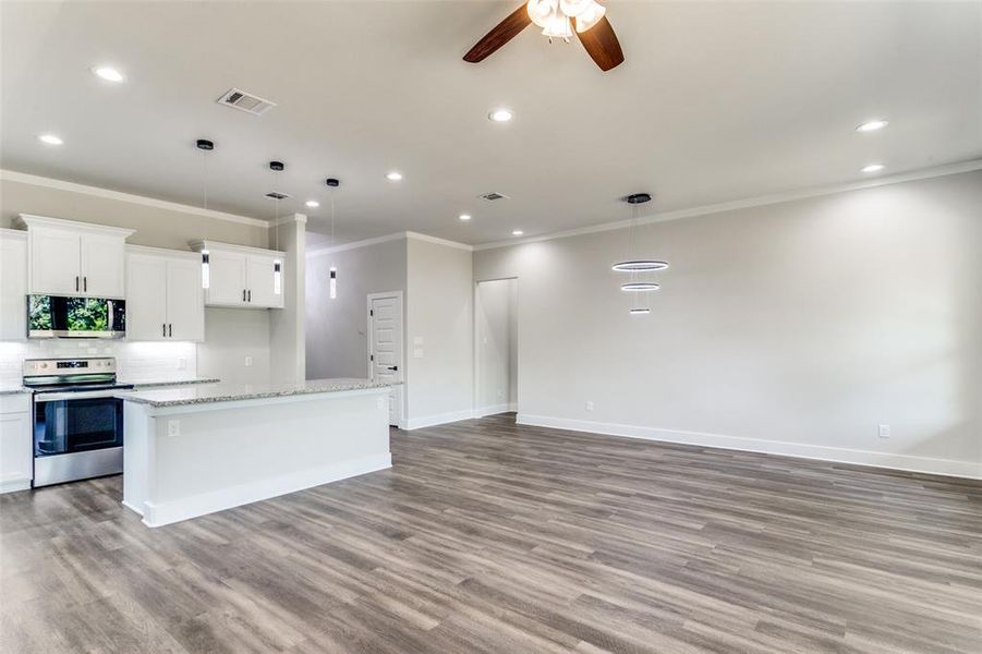 Kitchen with decorative backsplash, appliances with stainless steel finishes, ceiling fan, and light hardwood / wood-style floors