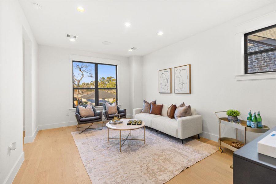 This is where your everyday living feels elevated—clean white walls, wide-plank wood floors, and oversized windows that pull in natural light all day long. The layout is perfectly scaled for comfortable seating without wasting space, making it easy to relax, entertain, or unwind at the end of the day.