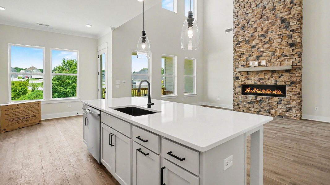 Kitchen with quartz countertops, pendant lighting, and view of gathering room Kitchen with quartz countertops, pendant lighting, and view of gathering room