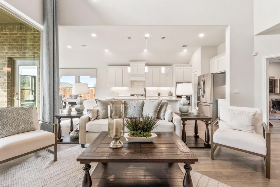 Open-concept living room with white sofa, wood coffee table, and kitchen visible in background Open-concept living room with white sofa, wood coffee table, and kitchen visible in background