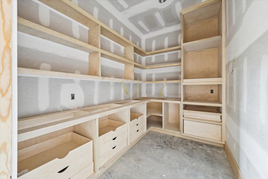 Expansive walk in pantry with custom built shelving, drawer storage, and wraparound countertop for small appliances. Designed for effortless organization while keeping the kitchen streamlined and clutter free.