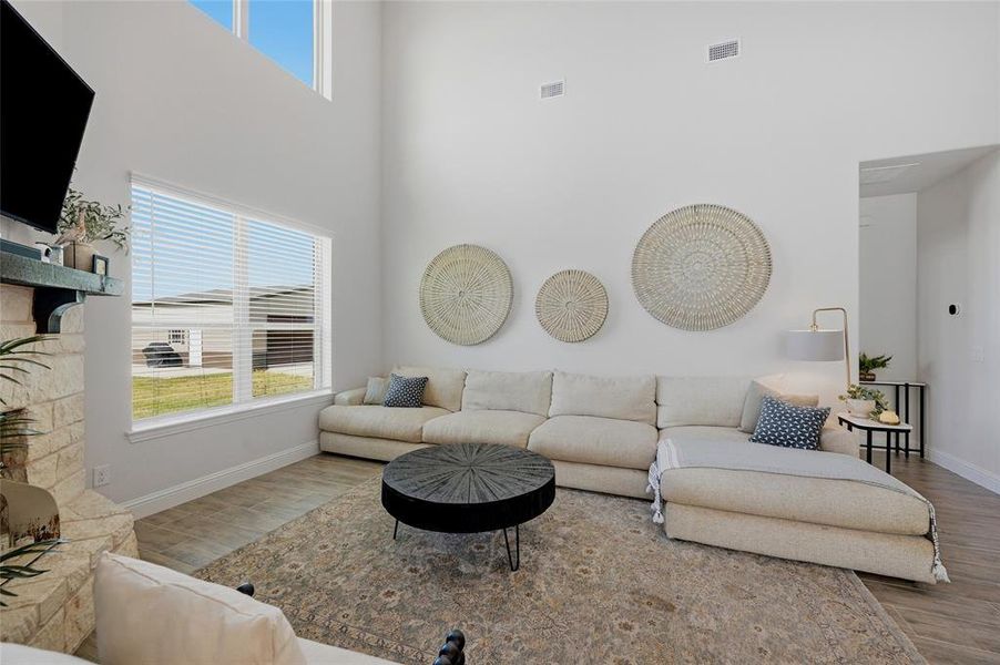 Vaulted ceiling living area featuring a stone-clad fireplace, a large rectangular window, and high-set windows