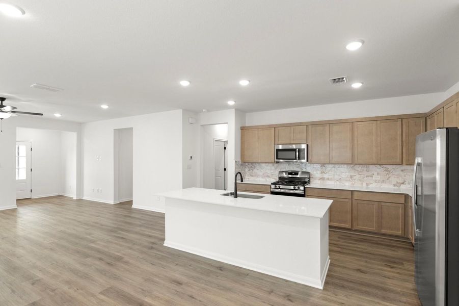 Kitchen featuring stainless steel appliances, an island with sink, open floor plan, decorative backsplash, and recessed lighting