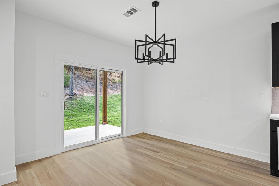 Unfurnished dining area featuring light wood-type flooring and a chandelier