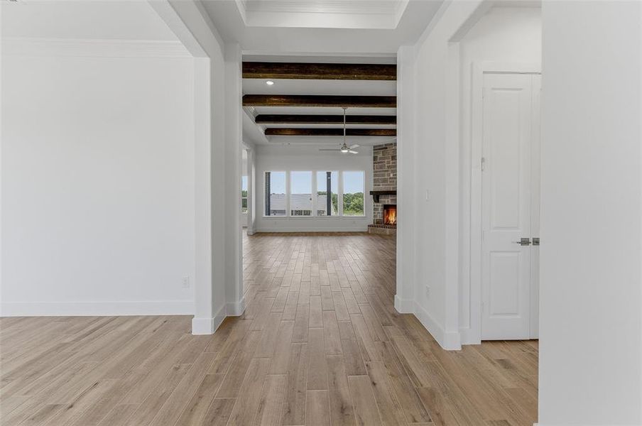 Expansive living area with wood-finish flooring, exposed ceiling beams, a stone-clad fireplace, and multiple windows