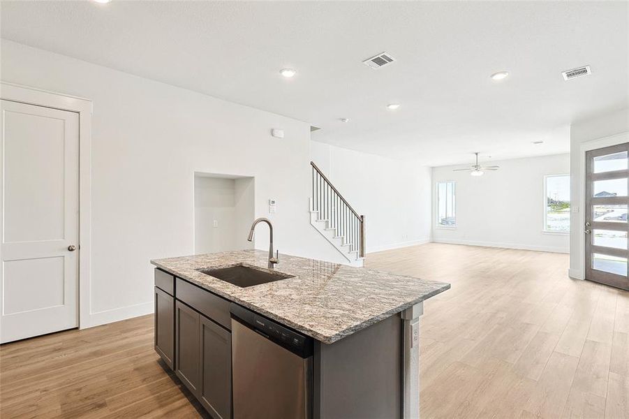 Kitchen with sink, light hardwood / wood-style floors, stainless steel dishwasher, a kitchen island with sink, and ceiling fan