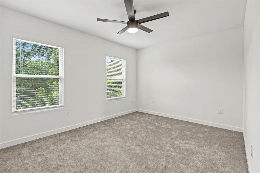 Carpeted spare room with a ceiling fan and baseboards Carpeted spare room with a ceiling fan and baseboards